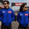 Aprilia MotoGP blue racing jacket worn by man and woman on racetrack with motorcycle in background motorsport style